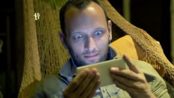 ハンモックのスマート フォン上のムービーを見ている男 — ストック動画