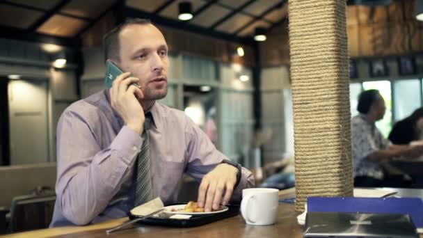 Geschäftsmann mit Handy isst Mittagessen im Café — Stockvideo