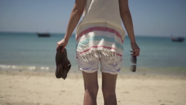 Kvinna med sandaler och solglasögon stående på stranden — Stockvideo