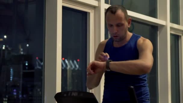 Man med smartwatch utövar på elliptisk maskin i gymmet — Stockvideo