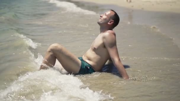 Bell'uomo rilassante e prendere il sole sulla spiaggia — Video Stock