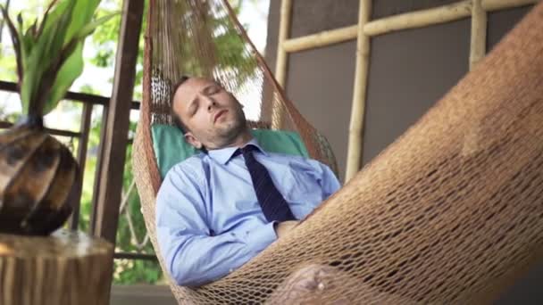 Joven hombre de negocios durmiendo en hamaca en terraza — Vídeos de Stock