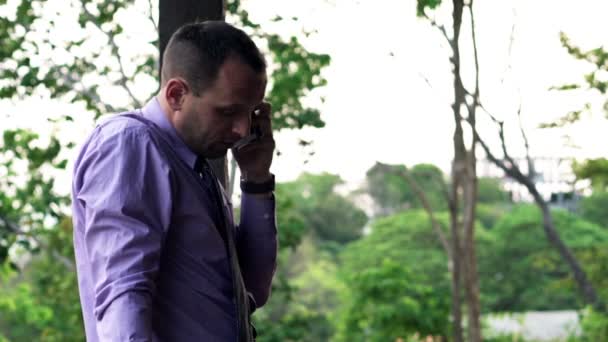 Молодой бизнесмен разговаривает по мобильному телефону на террасе — стоковое видео