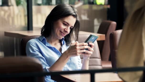Mujer usando el teléfono inteligente mientras está sentado en la cafetería — Vídeo de stock