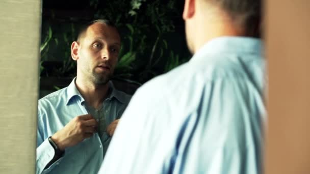 Бизнесмен надевает рубашку перед зеркалом — стоковое видео