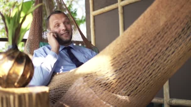 Hombre de negocios hablando por teléfono celular en hamaca — Vídeos de Stock