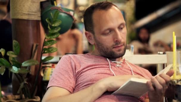 Hombre leyendo libro sentado en la cafetería — Vídeos de Stock