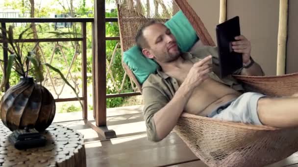 Hombre leyendo en el ordenador tableta y agua potable — Vídeos de Stock