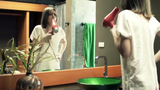 Женщина поет фен в ванной комнате — стоковое видео