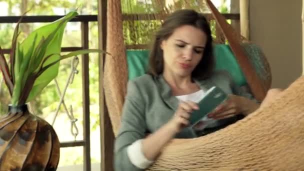 Молодая деловая женщина лежит на гамаке на террасе — стоковое видео