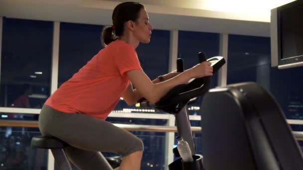 Femme en vélo stationnaire dans la salle de gym — Video