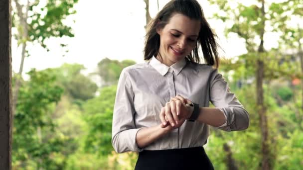 Bizneswoman z pokładzie smartwatch stojąc na tarasie — Wideo stockowe