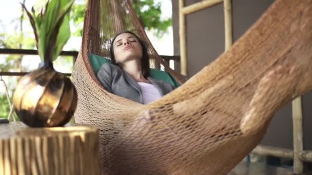 Young businesswoman sleeping on hammock on terrace — Stock Video