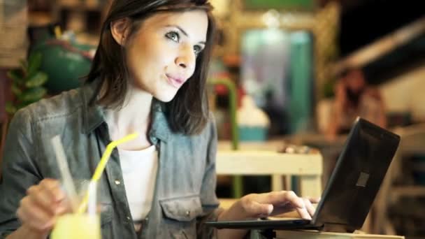 Woman using laptop and drinking cocktail — Stock Video