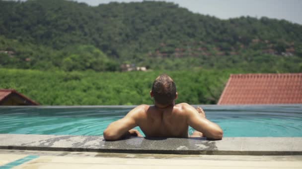 Homem tomando banho de sol, relaxando na piscina — Vídeo de Stock