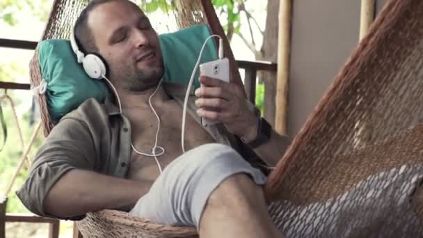 Hombre escuchando música y cantando en hamaca — Vídeo de stock