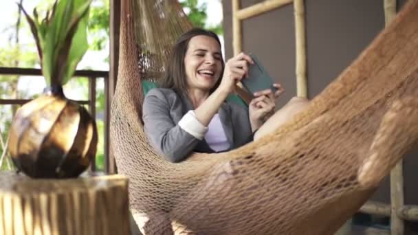 Businesswoman playing game on smartphone on hammock — Stock Video