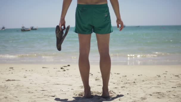 Hombre con chanclas de pie en la playa — Vídeos de Stock