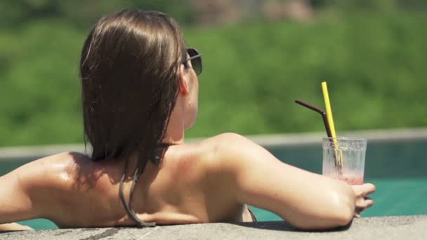 Woman in swimming pool relaxing and drinking cocktail — Stock Video