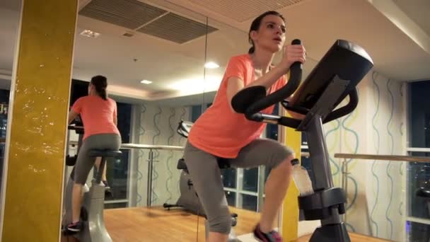 체육관에서 여자 승마 고정 자전거 — 비디오
