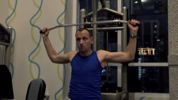 Hombre haciendo ejercicio en la máquina lat en el gimnasio — Vídeos de Stock