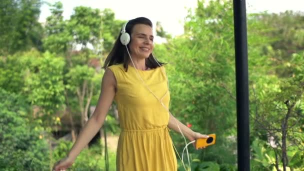 Kvinna lyssna på musik och dans på terrassen — Stockvideo