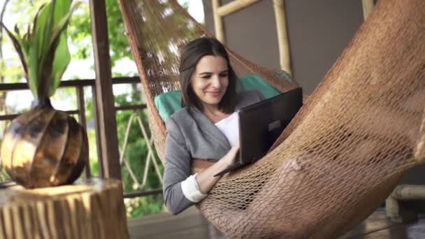 Mujer de negocios usando el ordenador portátil que miente en la hamaca — Vídeo de stock