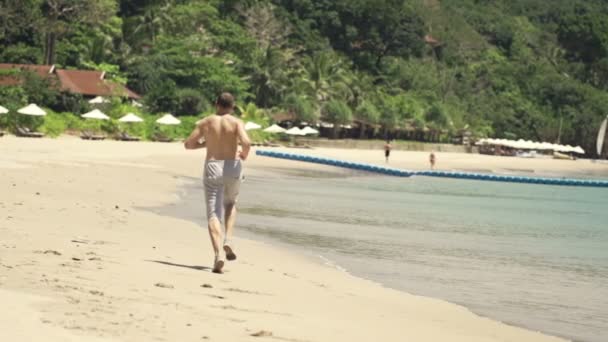 Hombre corriendo en hermosa playa — Vídeos de Stock