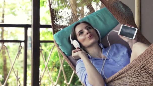 Kobieta słuchać muzyki leżącego na hamaku na tarasie — Wideo stockowe