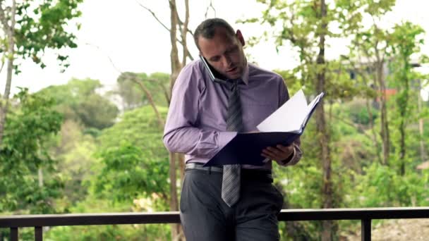 Businessman with documents talking on cellphone — Stock Video