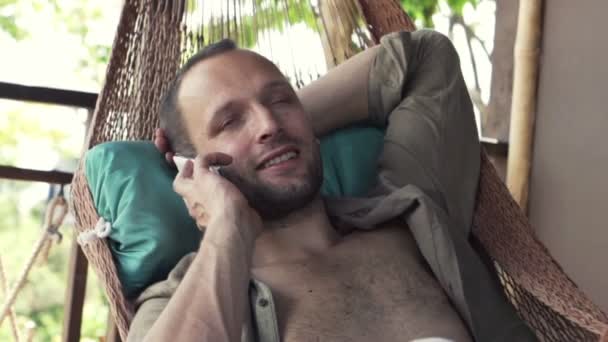 Man talking on cellphone while lying on hammock — Stock Video