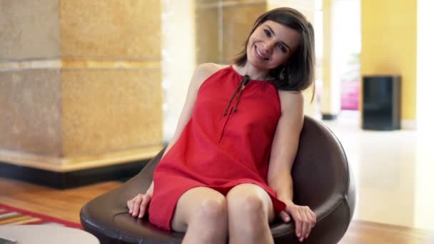 Woman sitting on chair at hotel reception — Stock Video