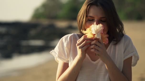 Mujer feliz oliendo flores en la playa — Vídeos de Stock