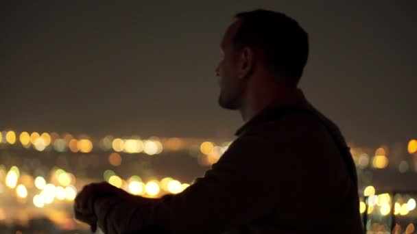 Joven mirando el paisaje urbano por la noche — Vídeos de Stock