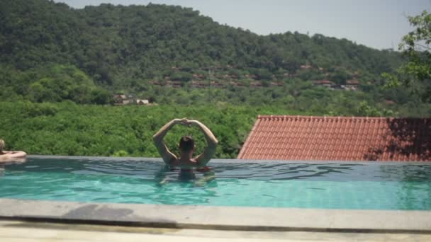 Hombre estirando los brazos y relajándose en la piscina — Vídeo de stock