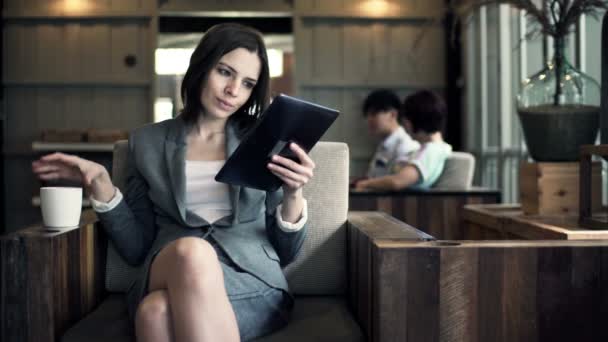 Mujer de negocios leyendo en la tableta y tomando café — Vídeo de stock