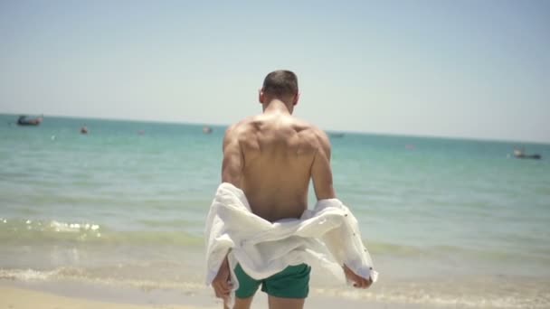 Hombre quitándose la camisa y corriendo al mar — Vídeos de Stock