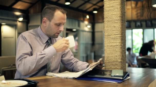 Επιχειρηματίας διαβάζοντας εφημερίδα και πίνοντας καφέ — Αρχείο Βίντεο