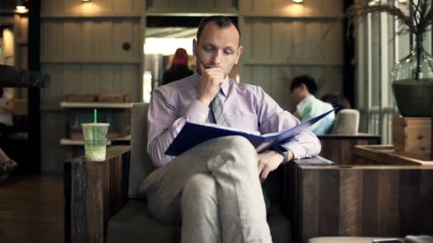 Businessman working with documents sitting in cafe — Stock Video