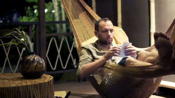 Hombre leyendo proyecto de ley mientras que miente en hamaca — Vídeos de Stock