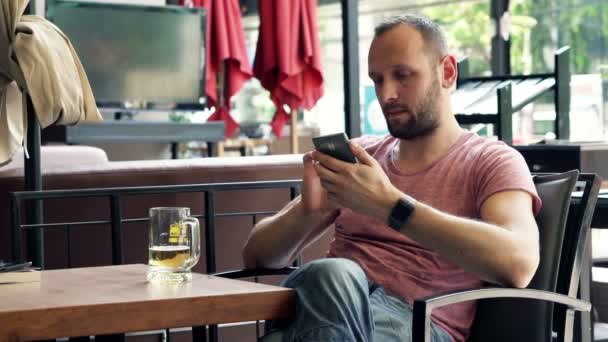 Man met smartphone zitten in Cafe — Stockvideo