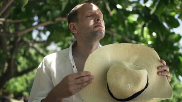 Man cooling himself with hat in park — Stock Video