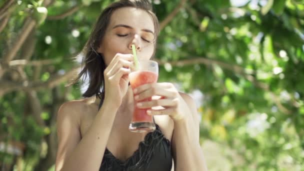 Woman drinking tropical cocktail in park — Stock Video