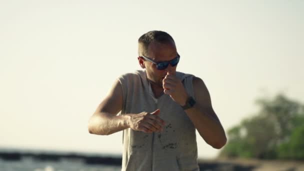 Jogger checking pulse on smartwatch on beach — Stock Video