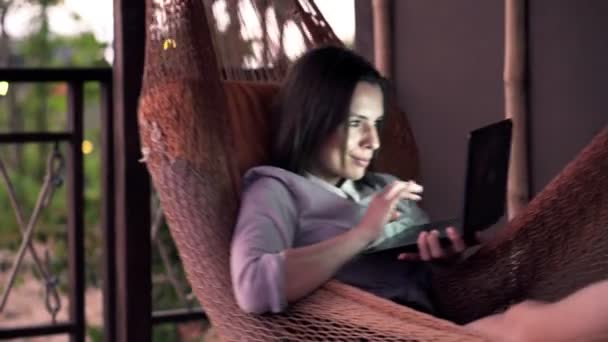Бизнесвумен работает на ноутбуке, лежа на гамаке — стоковое видео
