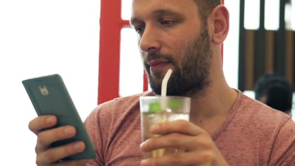 Hombre con teléfono inteligente beber cóctel en la cafetería — Vídeo de stock