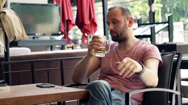 Triste homme boire de la bière assis dans le café — Video