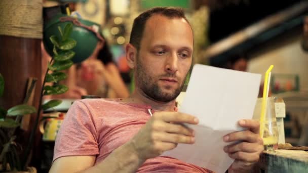 Чоловік читає рахунок, сидячи в кафе — стокове відео
