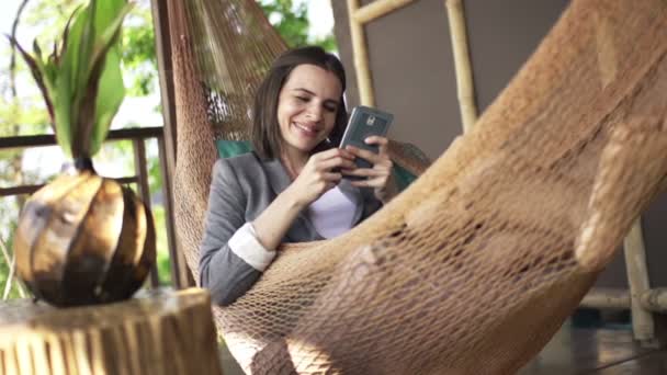 Бізнес-леді з смартфоном лежить на гамаку — стокове відео
