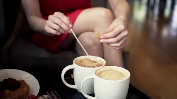 Vrouw handen toe te voegen suiker in koffie in het café — Stockvideo